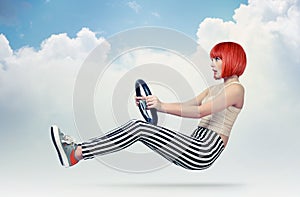 Young redhead girl driver car with a wheel in clouds, auto concept