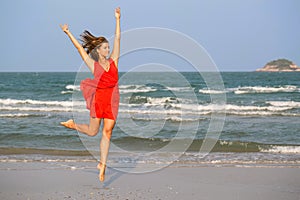 Young redhead girl jumping at the beach