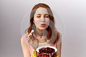 Young redhead girl with pleasure eating a cake in her hands. The concept of sweet tooth, healthy eating, weight control
