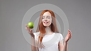 Young redhead girl tosses green Apple. Slow Motion