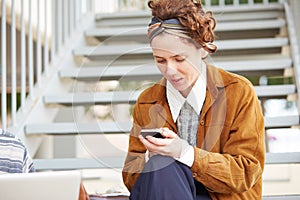 Young redhead hipster woman using smartphone