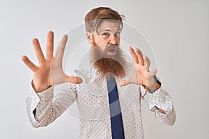 Young redhead irish businessman standing over isolated white background afraid and terrified with fear expression stop gesture