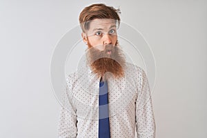 Young redhead irish businessman standing over isolated white background making fish face with lips, crazy and comical gesture