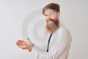 Young redhead irish businessman standing over isolated white background pointing aside with hands open palms showing copy space,