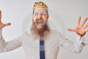 Young redhead irish businessman wearing crown king over isolated white background celebrating mad and crazy for success with arms