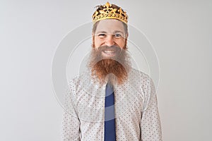 Young redhead irish businessman wearing crown king over isolated white background with a happy and cool smile on face