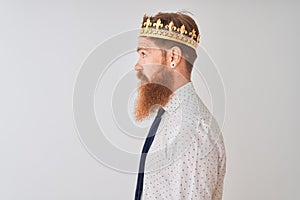 Young redhead irish businessman wearing crown king over isolated white background looking to side, relax profile pose with natural