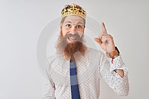 Young redhead irish businessman wearing crown king over isolated white background pointing finger up with successful idea
