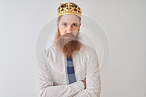 Young redhead irish businessman wearing crown king over isolated white background skeptic and nervous, disapproving expression on