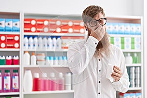 Young redhead man customer using nakpin at pharmacy