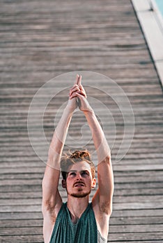 Young redhead man sportsman performing the Namaste Yoga greeting while practicing on a city street