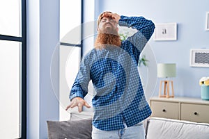 Young redhead man suffering dizzy standing at home