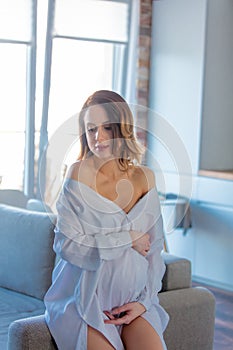 Young redhead pregnant woman in white clothes