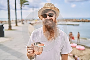 Young redhead tourist man smiling happy drinking cocktail at the beach