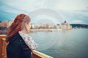 Young redhead woman at autumn take pleasure in Budapest cityscape