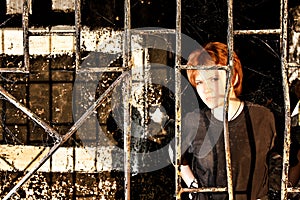 Young redhead woman behind bars