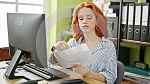 Young redhead woman business worker using computer opening envelope letter at office