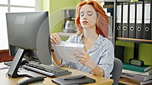 Young redhead woman business worker using computer opening envelope letter at office
