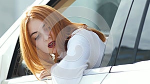 Young redhead woman driver driving a car backwards looking behind
