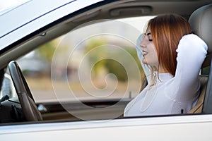 Young redhead woman driver fastened by seatbelt resting in a car smiling happily