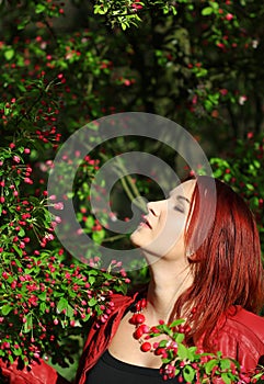 Young redhead woman enjoying cherry blossom in the sunshi