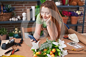 Young redhead woman florist smiling confident using smartphone at flower shop