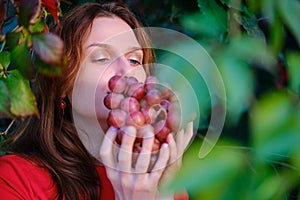Young redhead woman harvests grapes, portrait