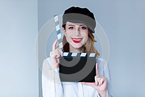 Young redhead woman in hat holding movie clapboard