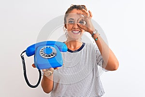 Young redhead woman holding classic retro telephone over isolated background with happy face smiling doing ok sign with hand on