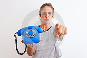 Young redhead woman holding classic retro telephone over isolated background pointing with finger to the camera and to you, hand