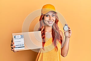 Young redhead woman holding delivery package and stopwatch smiling with a happy and cool smile on face