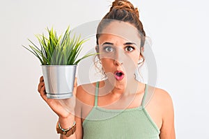 Young redhead woman holding plant pot over isolated background scared in shock with a surprise face, afraid and excited with fear