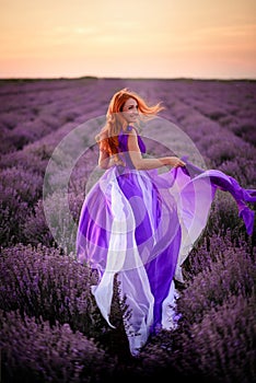 Young woman in luxurious purple dress standing in lavender field, rear view