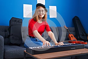 Young redhead woman musician smiling confident playing piano at music studio