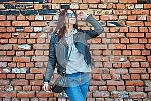 Young redhead woman posing near the brick wall