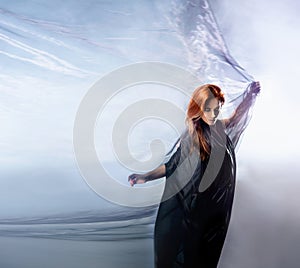 A young redhead woman posing in a silk dress