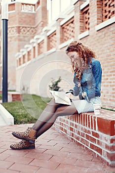 Young redhead woman reading book in park sitting and smiling