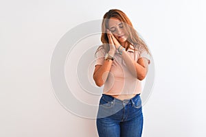 Young redhead woman stading over white isolated background sleeping tired dreaming and posing with hands together while smiling