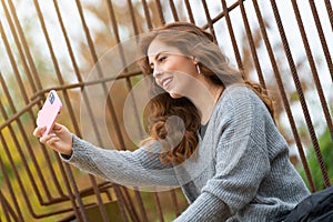 Young redhead woman taking a selfie sitting in the park