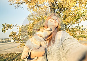 Young redhead woman taking surprised selfie outdoors with dog