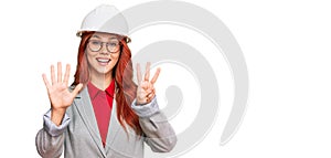 Young redhead woman wearing architect hardhat showing and pointing up with fingers number eight while smiling confident and happy
