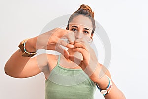 Young redhead woman wearing a bun over isolated background smiling in love showing heart symbol and shape with hands