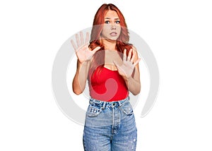 Young redhead woman wearing casual clothes afraid and terrified with fear expression stop gesture with hands, shouting in shock