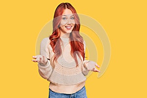 Young redhead woman wearing casual winter sweater smiling cheerful with open arms as friendly welcome, positive and confident