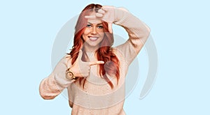 Young redhead woman wearing casual winter sweater smiling making frame with hands and fingers with happy face