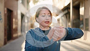 Young redhead woman wearing sportswear looking stopwatch at street