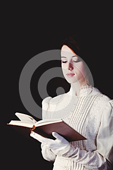 Woman in white Victorian era clothes with book