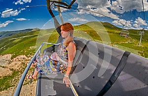 Young redheaded woman enjoying a ride on an open-air ropeway