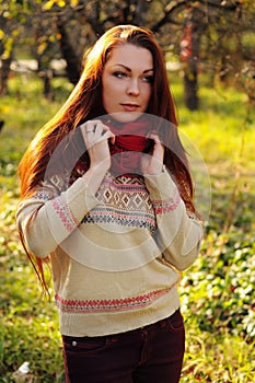 Young redheaded woman with long straight hair in the apple garden