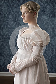 A young Regency woman in a pink dress and pearl necklace